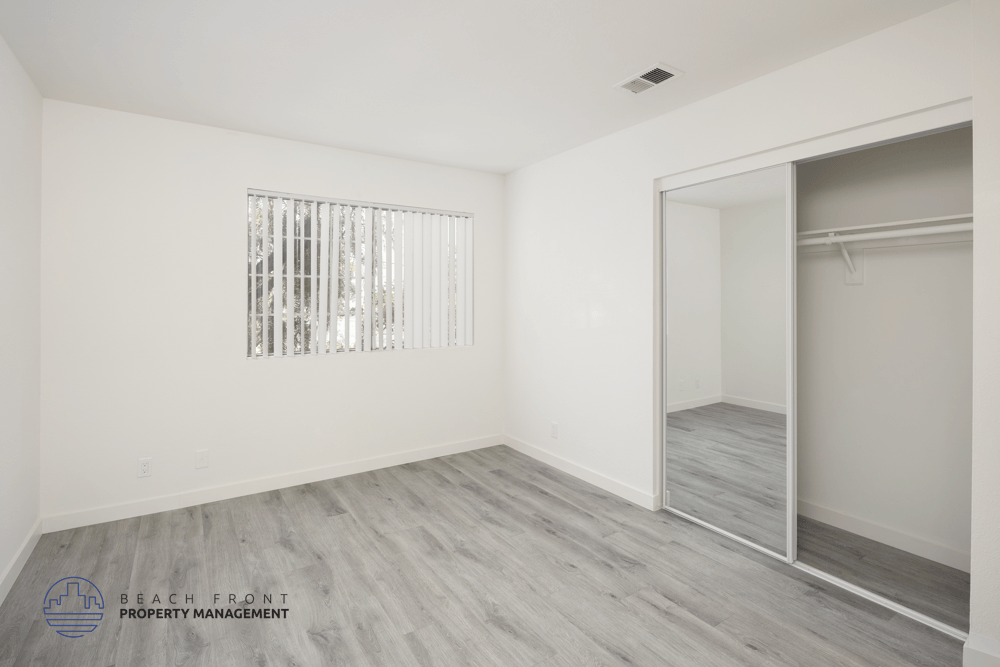 A sparsely furnished room with a sliding door and a window with bars.